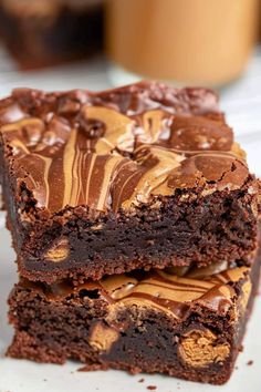 two pieces of chocolate brownie on a white plate with peanut butter swirled in the middle