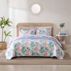 a bed in a room with white walls and plants on the floor next to it