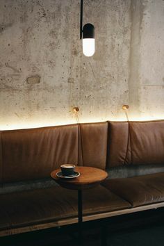 a table with a coffee cup sitting on top of it next to a brown leather couch