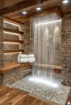 a bathroom with stone walls and a waterfall in the center, surrounded by wood flooring