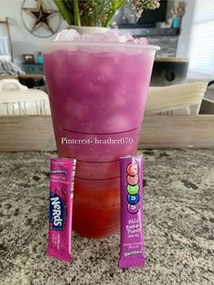 a pink drink in a tall glass with ice and candy bars on the rim next to it