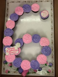 a birthday cake decorated with cupcakes in the shape of a heart and flowers