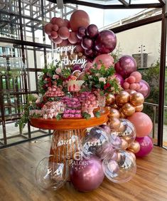 a table topped with lots of pink and gold balloons