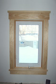 a window in the corner of a room with wood trimmings on the wall