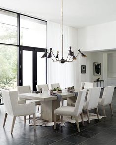 a dining room table with white chairs and a chandelier hanging from the ceiling