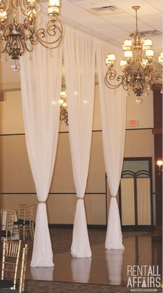 an empty ballroom with chandeliers and white drapes