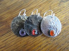 "Here are earrings made from sterling silver that I textured with a lace-like pattern. I made three pairs with 6mm stones. You have your choice of red garnet, orange carnelian, or purple amethyst.T he ear wire is handmade of sterling silver. The earrings are antiqued and hand polished to emphasize the texture. Disc measures 7/8\" (22 mm) Lightweight and easy to wear." Silver Round Carnelian Earrings, Silver Carnelian Earrings For Gift, Orange Carnelian, Sterling Silver Dangle Earrings, Agate Necklace, Silver Earrings Dangle, Red Garnet, Baroque Pearls, Ear Wire