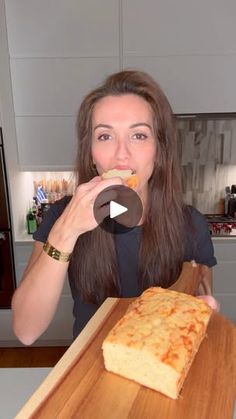 a woman eating a piece of pizza on top of a wooden cutting board