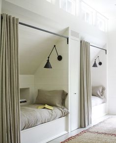 an attic bedroom with two beds and hanging lights on the wall above them, along with a rug