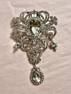 This absolutely awesome and unique brooch is extra large at 5 inches. There is a loop for a ribbon or necklace chain, and a pin back.   This can also be sewn to a costume or dress and sometimes called a stomacher.  There is a large center crystal and three drops. It is 3 dimensional and a real statement piece.  This would look great on a button up shirt, a hat accessory, a bouquet accent and a bridal gown. Colors available: gold, silver, rose gold Ornate Wedding Brooches With Jewels, Wedding Pendant Brooches, Elegant Large Pendant Brooches As Gifts, Elegant Large Pendant Brooches For Gifts, Crystal Costume Jewelry Brooch, Crystal Brooch Costume Jewelry, Crystal Brooch In Costume Jewelry Style, Glamorous Silver Brooch For Wedding, Glamorous Silver Brooch Jewelry