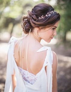 the back of a woman wearing a white dress and a headpiece with flowers on it