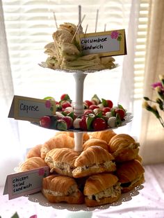 three tiered trays filled with sandwiches and croissants on top of each other