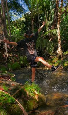 a man riding a skateboard across a river surrounded by trees and plants in the forest