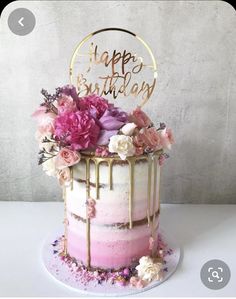 a birthday cake decorated with flowers and the words happy birthday written on top in gold