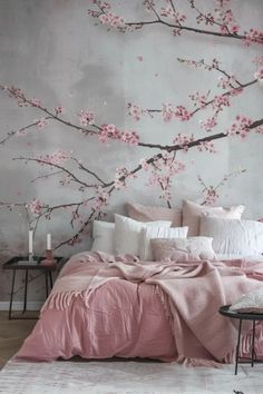 a bed with pink comforter and pillows in front of a wall mural that has flowers on it