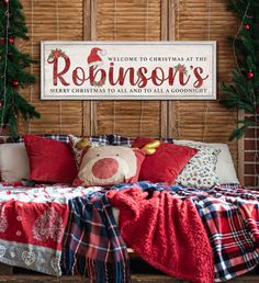 a bed covered in blankets and pillows under a christmas sign