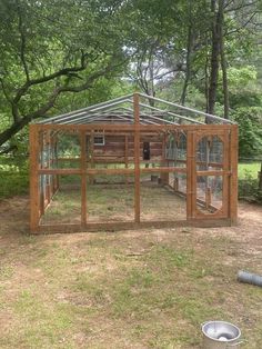 a chicken coop built into the side of a field with trees in the back ground