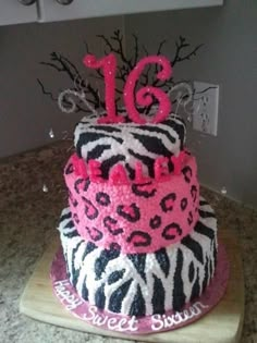 a birthday cake decorated with zebra print and pink icing, on top of a cutting board