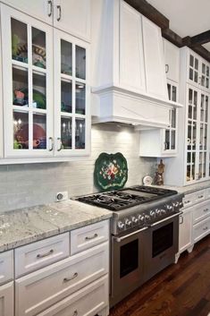 a kitchen with white cabinets and marble counter tops, along with stainless steel stove top oven