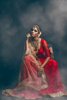 a woman in a red dress sitting on top of a cloud filled sky with her hands to her face