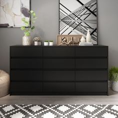 a black dresser sitting in a living room next to a chair and painting on the wall