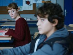 two young boys sitting at desks in a classroom