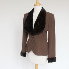 "A long fitted jacket from the 40's with a sheared fur or fleece collar and cuffs. Beautiful vintage styling. Wear it with jeans and boots for a night out or with a skirt and heels to the office. It's a great option for a spring or fall outer jacket. The brown wool jacket is fitted through the waist, has covered buttons, and bound button holes.The brown fur lapels form a lovely collar effect and the cuffs add to the stylish look. The cuffs are snug fitting at the wrist. It is lined with a rust b Vintage Fitted Outerwear With Faux Fur Lining, Vintage Fitted Outerwear With Padded Collar, Vintage Winter Outerwear For Formal Occasions, Retro Tailored Winter Outerwear, Fitted Winter Outerwear For Vintage Fashion, Vintage Outerwear For Formal Winter Occasions, Formal Vintage Outerwear With Faux Fur Trim, Retro Fitted Winter Outerwear, Vintage Formal Winter Outerwear