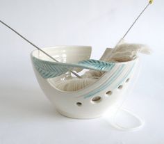 a white bowl with yarn and needles in it