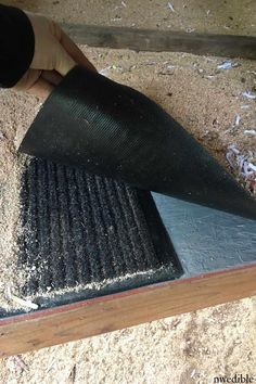 a person is sanding up the floor with a large piece of black material on top of it