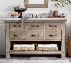 a bathroom vanity with drawers and two baskets under the sink, in front of a mirror