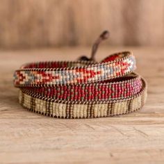 three woven bracelets sitting on top of a wooden table