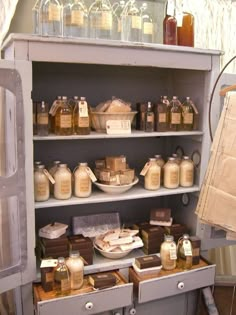 an old fashioned cabinet with lots of bottles and jars on the top shelf in front of it