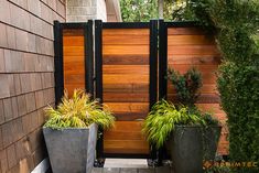 two large planters sitting next to each other in front of a wooden fenced entrance