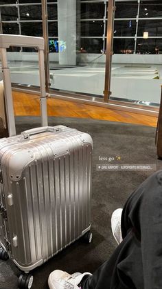 a person sitting on the ground with their feet up next to a luggage bag and suitcase