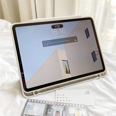 an open laptop computer sitting on top of a white bed next to a movie strip