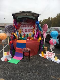 a candy land display in the parking lot with balloons and streamers all around it