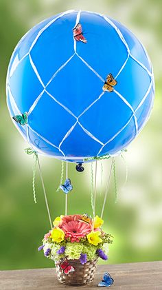 a blue hot air balloon sitting on top of a table next to a basket filled with flowers