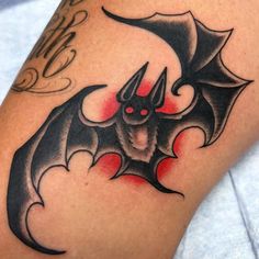 a bat tattoo on the leg of a person with red eyes and black bats around it