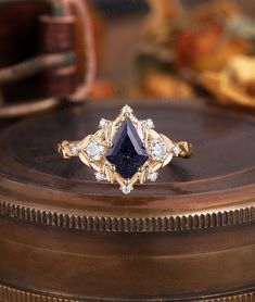 a diamond and blue sapphire ring sitting on top of a wooden box with other items in the background