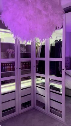 the closet is filled with lots of clothes and other items in purple lighting, as well as a feather chandelier