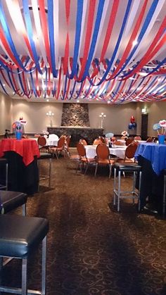 a room filled with lots of tables covered in red, white and blue streamers