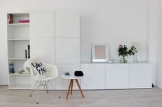 a living room with white furniture and bookshelf in the backround area