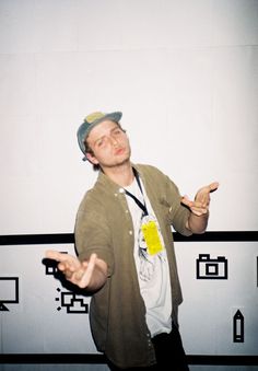 a man standing in front of a white wall holding his hands out to the side