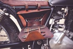 a close up of a motorcycle with a leather bag on it's back seat