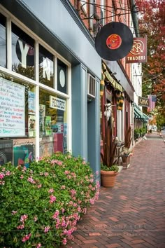 a store front with flowers in the foreground