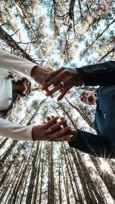 two people holding hands in the middle of a forest