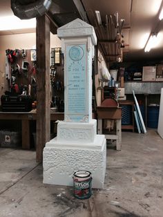 a white monument with a blue plaque on it in a garage next to a can of paint