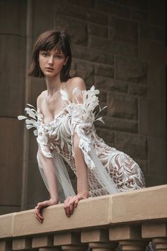 a woman in a white dress leaning on a ledge