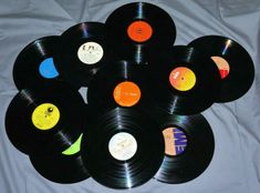 a pile of black records sitting on top of a white bed cover covered in colorful stickers