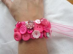 a woman's arm wearing a pink bracelet with buttons on it